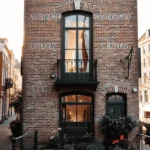 Image showing the most narrow house in Amsterdam with the narrow building in the background and the framed portrait of the owner displayed at the front.