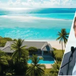 Image showing the john mcafee belize house with the tropical-style home in the background and a framed portrait of John McAfee placed prominently in the foreground.